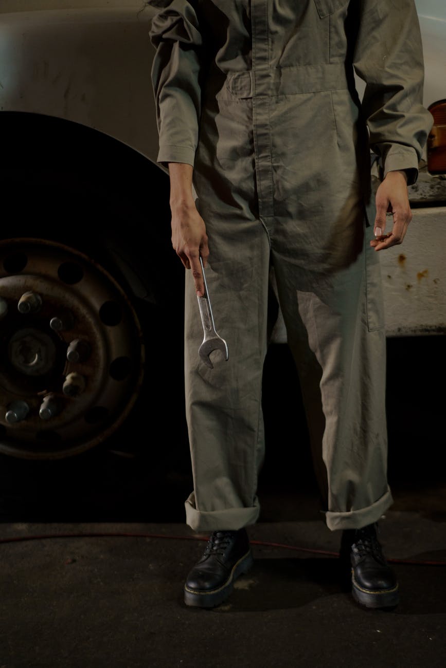 person wearing gray coverall holding a wrench