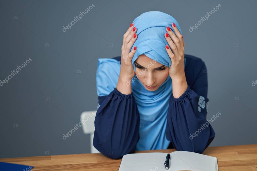 Unhappy muslim female student learning at home