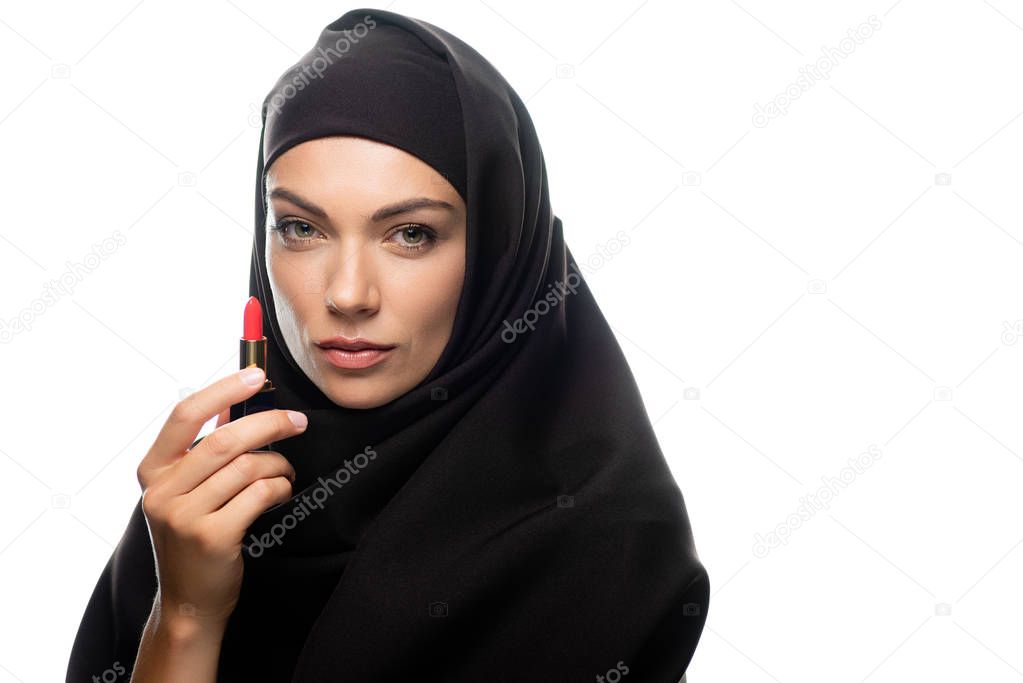 young Muslim woman in hijab holding red lipstick isolated on white