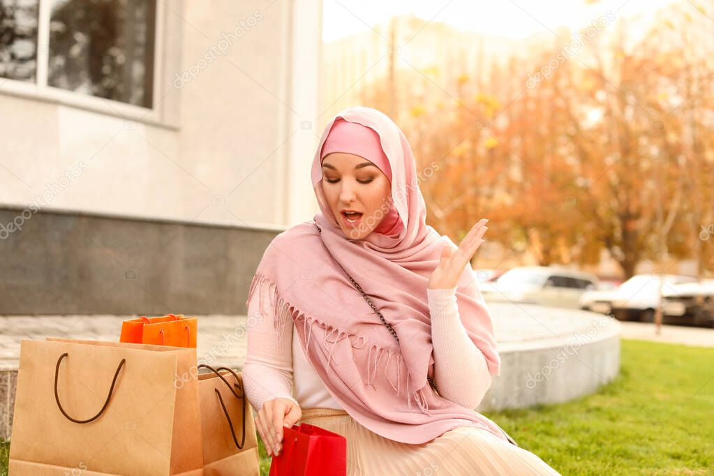 Beautiful Muslim woman with shopping bags outdoors